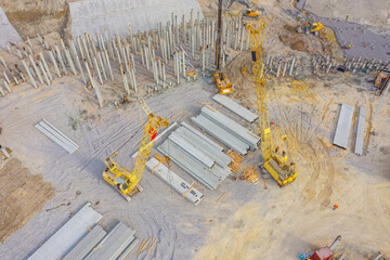 Equipment for installing piles in ground, heavy machines for driving pillars work in laying the foundation building. Construction aerial view height.