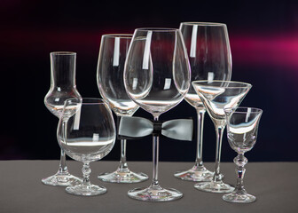 Alcohol glasses with bow tie isolated on black background. International Bartenders Day.