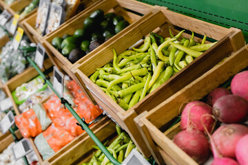 Fresh peppers on counter in supermarket on blurred background