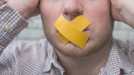 A man with duct tape on his mouth, a man with duct tape on his lips. The man's mouth is closed