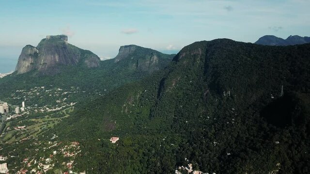 Aerial drone footage of Favela da Rocinha slum surrounded by green rocky mountains on a sunny day in Rio de Janeiro, Brazil. City urban scenery.