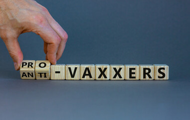 Pro-vaxxers or anti-vaxxers symbol. Doctor turns cubes, changes words 'anti-vaxxers' to 'pro-vaxxers'. Beautiful grey background. Copy space. Medical covid-19 pro-vaxxers or anti-vaxxers concept.