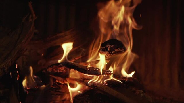 Burning real wood fire with sparks jumping at a fireplace in a hotel living room in Spain. Close up of flames burning in slow motion at 120fps background footage.Concept of calm, cozy and warm place.