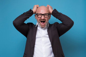 Mature caucasian businessman worried with a bad business news, isolated over a blue background
