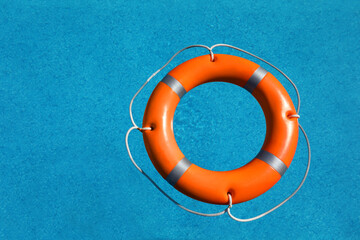 Bright orange inflatable ring floating in swimming pool, top view