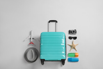 Flat lay composition with suitcase and travel accessories on grey background. Summer vacation