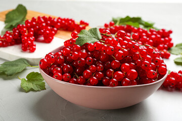 Delicious red currants in bowl on light table