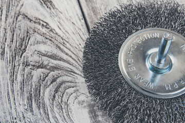 Wire brush for of electric drill on wooden background, macro, closeup