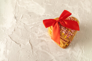 cookies in the shape of hearts decorated with glaze with a bow on a concrete texture background, place for text confectionery, dessert, festive background