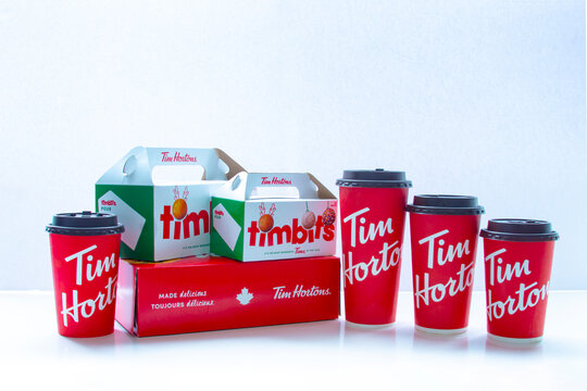Calgary, Alberta. Canada. Jan 28, 2021. Several Tim Hortons coffee cups in different sizes with boxes of timbits and donuts on a white background.