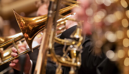 Trumpet professional player with symphony orchestra performing in concert on background. - obrazy, fototapety, plakaty