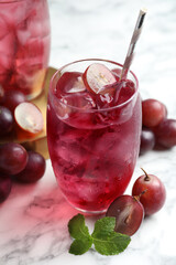 Delicious grape soda water with mint and berries on white marble table. Refreshing drink