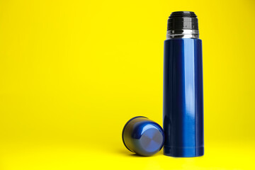 Stylish thermo bottle on yellow background, space for text