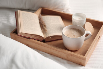 Cup of aromatic coffee, book and candle on white blanket, closeup