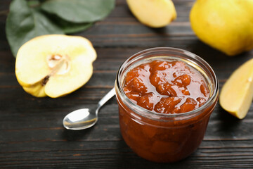 Delicious quince jam and fruits on black wooden table. Space for text