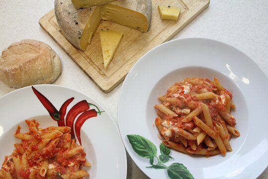 Two Pasta Plates, Pasta Dish With Tomato Sauce, Bun And Large Cheese In The Background, Italian Pasta Dish