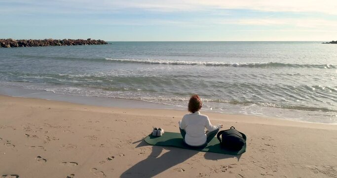 Vista de espalda con dron de mujer de mediana edad sentada reflexionando delante del sol
