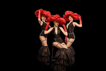 Three beautiful cabaret dancers in red hats isolated on black