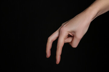 Fototapeta na wymiar Woman imitating walk with hand on black background, closeup. Finger gesture