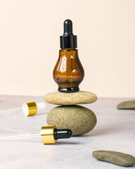 Medical cosmetic product in a bottle with a pipette on a beige background. Essential natural oil in a brown bottle on a stone.