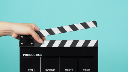  Hand is holding Black clapper board or clapperboard or movie slate on green or Turquoise...