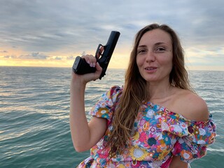 Girl with a pistol on the background of the sea
