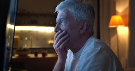 Close up of disappointed aged man watching tv news sitting near screen - Powered by Adobe