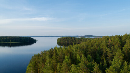 Beautiful aerial view of an island and forest. Lake, coastline and reflection in calm water.