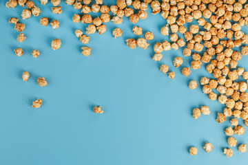 Caramel popcorn by a ripple on a blue background, in the form of a frame.