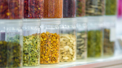 Dried vegetables in glass jars, onions, beets, carrots, pumpkin, bay leaf, banks on blurred background. Superfoods, herbs.