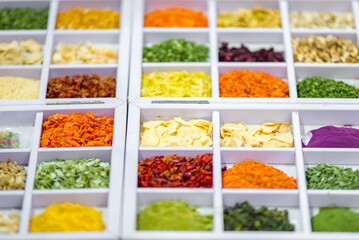 Dried vegetables in glass jars, onions, beets, carrots, pumpkin, bay leaf, banks on straw napkin and wooden background. Superfoods, herbs.