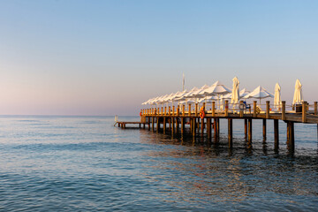 Pier with white umbrellas and sunbeds in luxury beach hotel in Antalya, Turkey