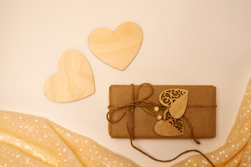 Gift box in craft paper on a light background, wooden hearts