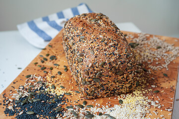 Freshly baked organic sourdough loaf of multi-seeded bread on wooden board.