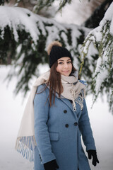 Pretty woman in blue coat walking in the woods on a winter snowy day. Beautiful woman posing to photographer