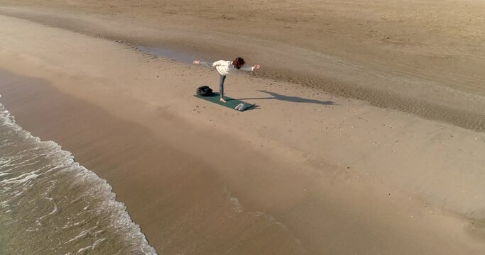 Mujer en la playa solitaria postura equilibrio de yoga y dron orbitando