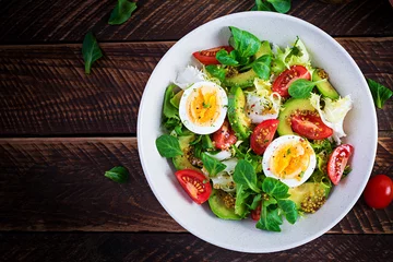 Foto auf Alu-Dibond Fresh avocado salad with tomato, avocado, boiled eggs and fresh lettuce. Ketogenic diet breakfast.  Keto, paleo salad. Top view, overhead, above © timolina
