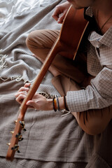 Man playing acoustic guitar at home on bed cozy