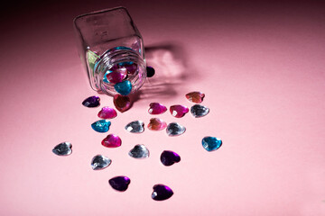 open glass flask heart-shaped plastic crystals coming out of it
