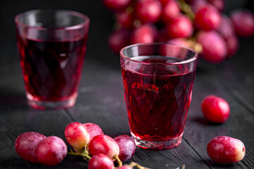 A glass of fresh grape juice, grape juice canning. Dark background, splashes and drops in a glass.
