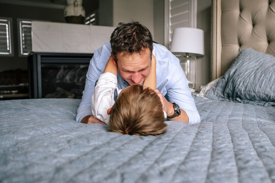 Happy Dad and son playing on bed