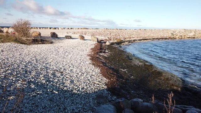 Panning shot over oresund Malmo, Sweden from rocky coast. View of a the radar post and the turning torso in the horizon on a bright day.