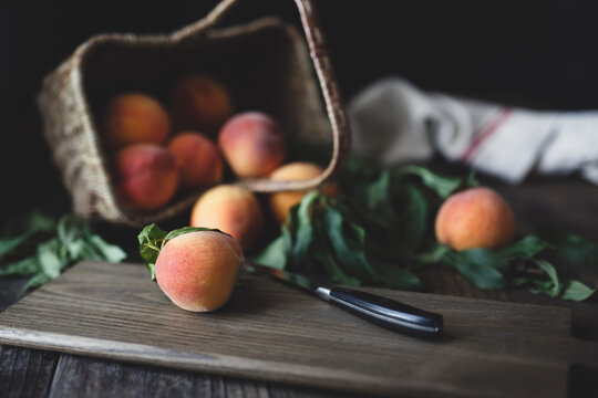fresh peaches in tipped basket and on cutting board with knife