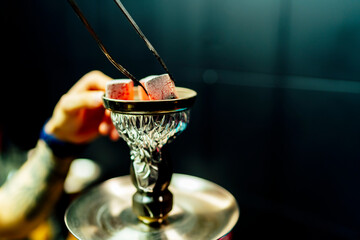 waiter placing smoking charcoal stones for shisha