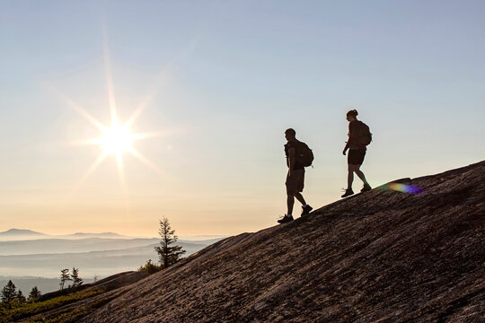 Two hikers descend mountain at sunrise on Appalachian Trail, Maine