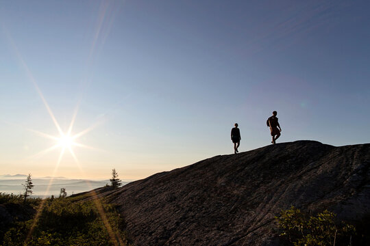 Couple walks at sunrise on mountain summit Appalachian Trail Maine