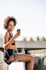 Athlete woman using her mobile phone outdoors.