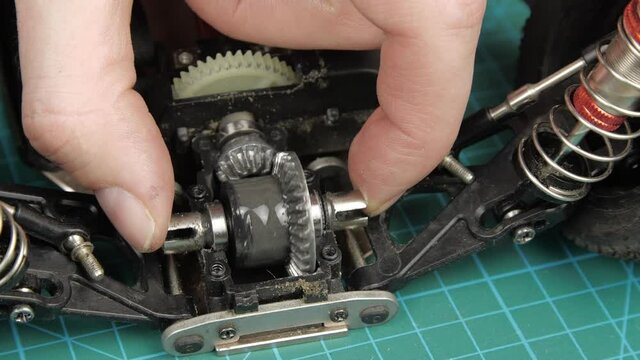 Close-up radio control model buggy car. The hands of the master disassemble the differential