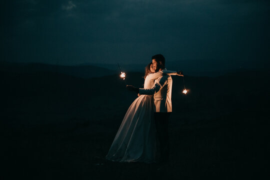 Young Couple Playing with Fireworks at night after the Wedding