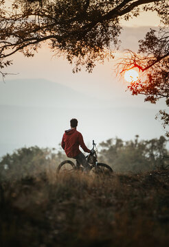 Young Biker Sitting on his Bike at Sunset During Autumn